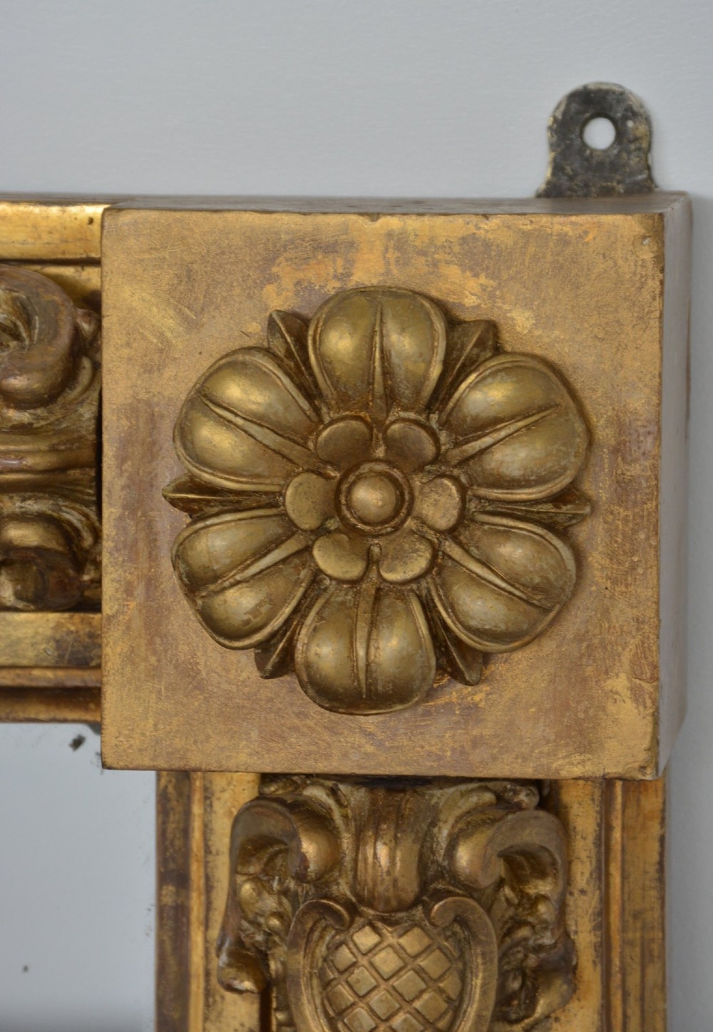 A large horizontal Regency style mirror featuring a gilded frame decorated with corner rosettes and floral mouldings enclosing foxed mirror glass. View VII