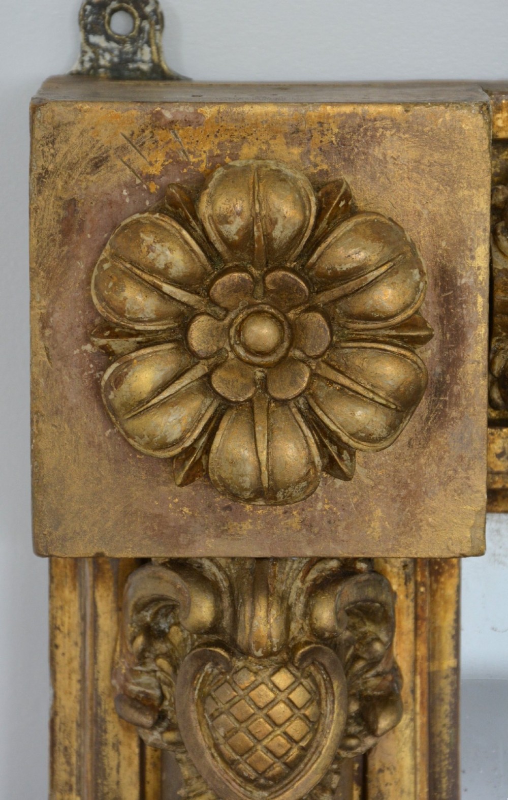 A large horizontal Regency style mirror featuring a gilded frame decorated with corner rosettes and floral mouldings enclosing foxed mirror glass. View VIII