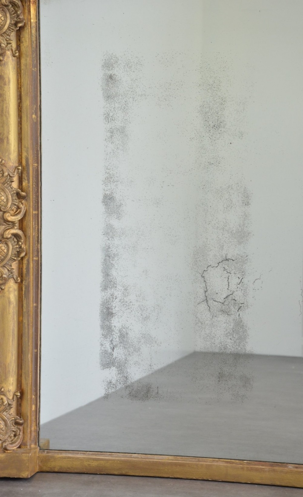 A large horizontal Regency style mirror featuring a gilded frame decorated with corner rosettes and floral mouldings enclosing foxed mirror glass. View XI