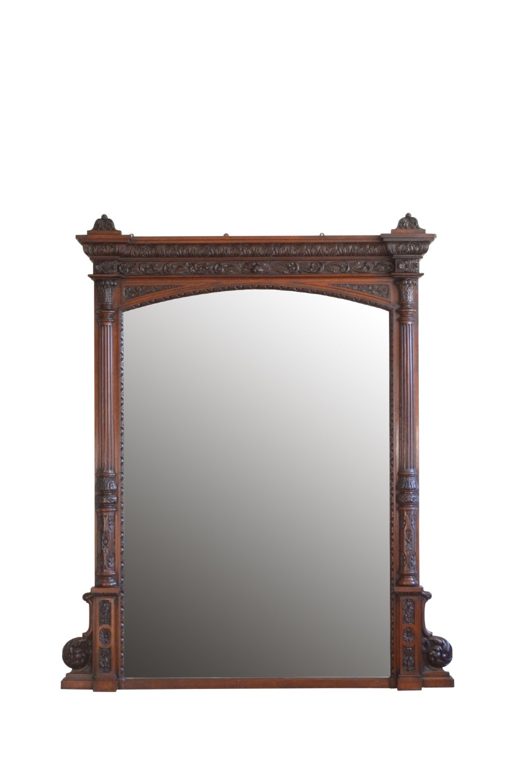 A tall 19th-century English solid oak mirror featuring an arched top, fluted column sides, and detailed hand-carved woodwork. View V
