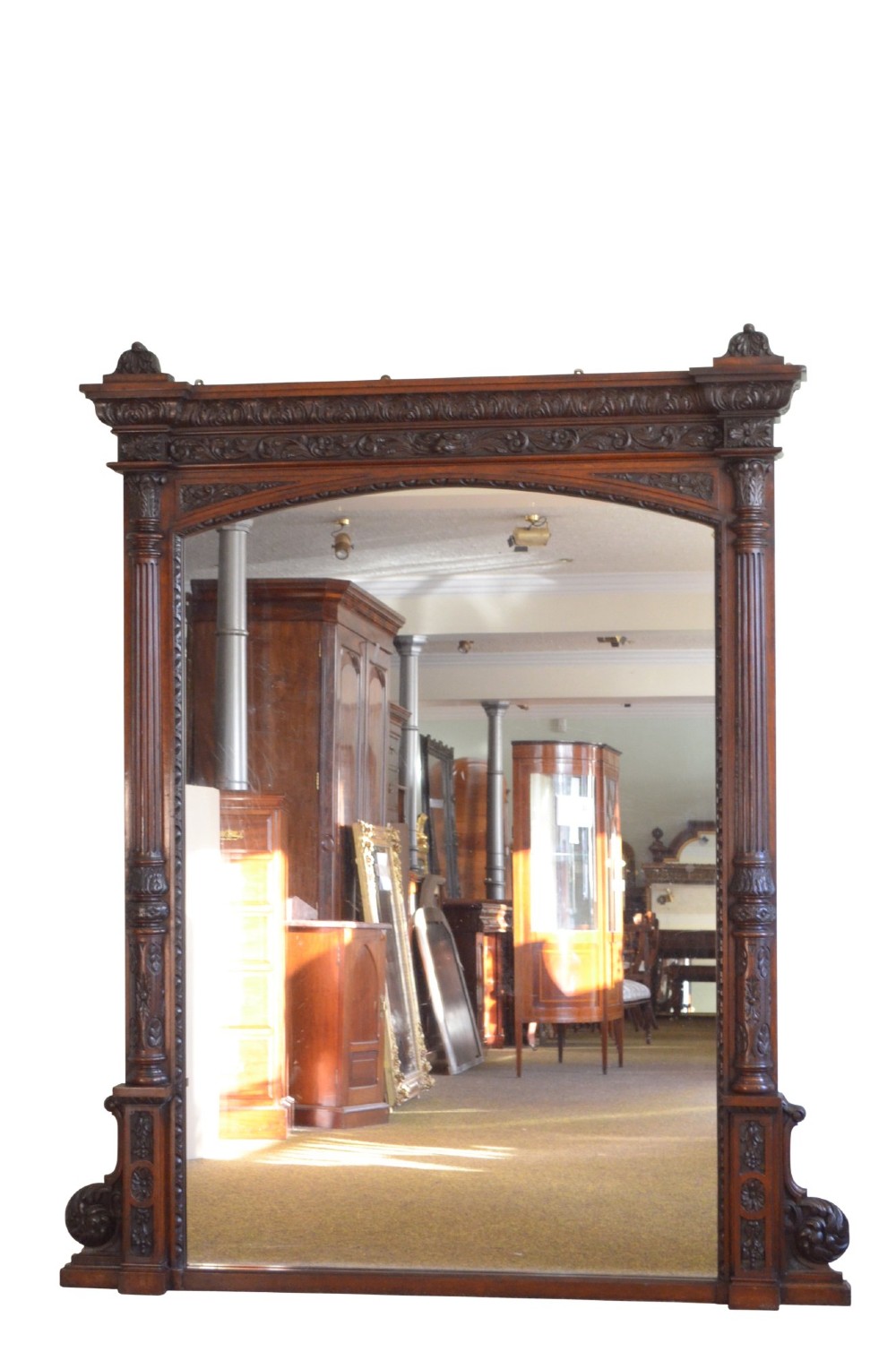 A tall 19th-century English solid oak mirror featuring an arched top, fluted column sides, and detailed hand-carved woodwork.