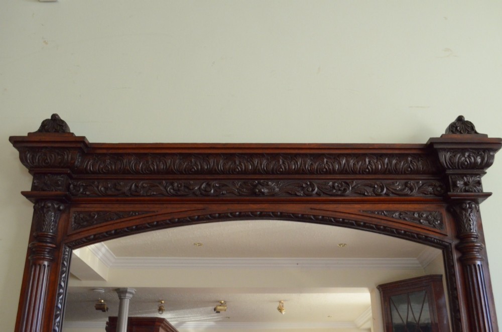 A tall 19th-century English solid oak mirror featuring an arched top, fluted column sides, and detailed hand-carved woodwork. View XI