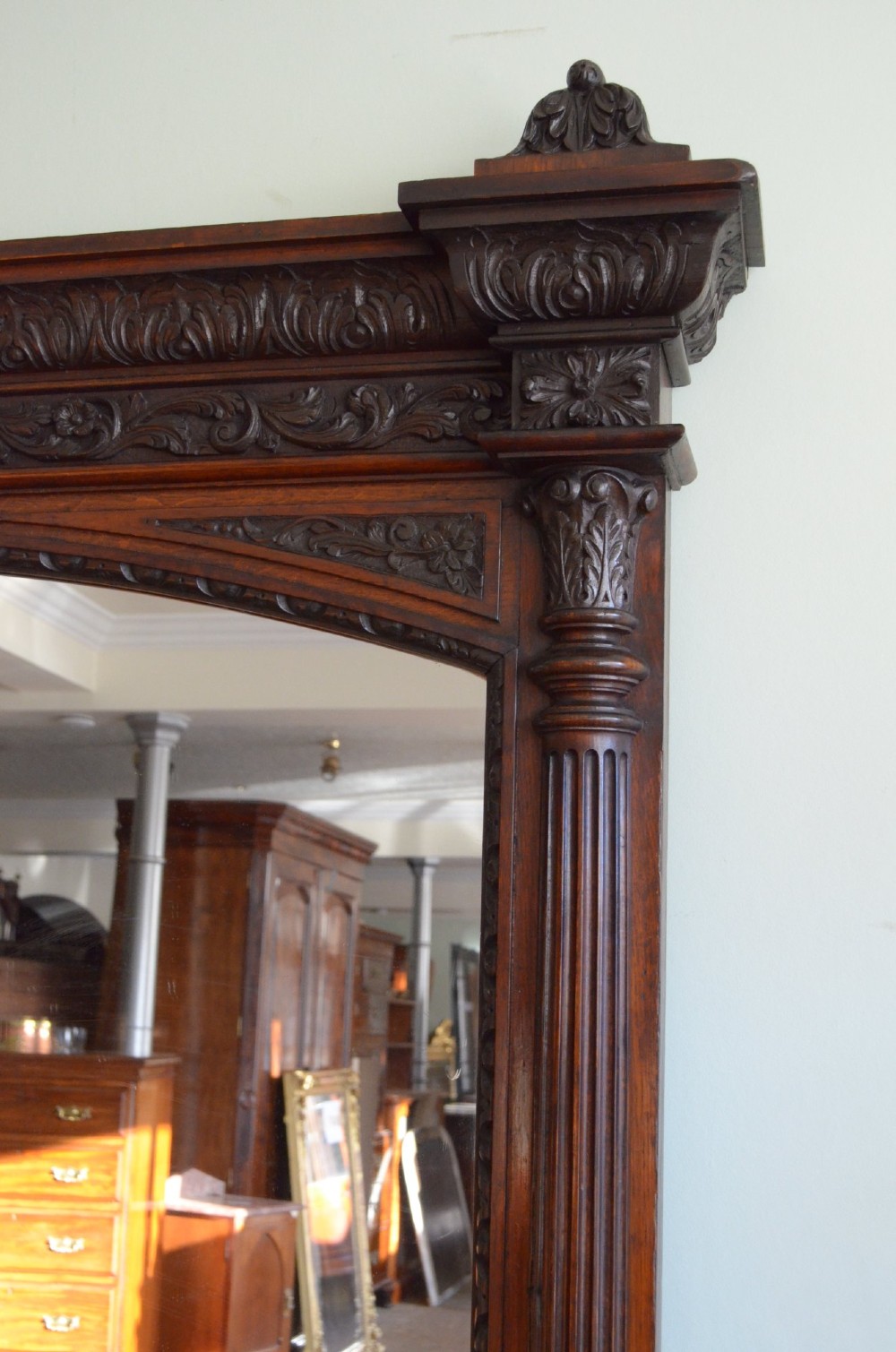 A tall 19th-century English solid oak mirror featuring an arched top, fluted column sides, and detailed hand-carved woodwork. View XII