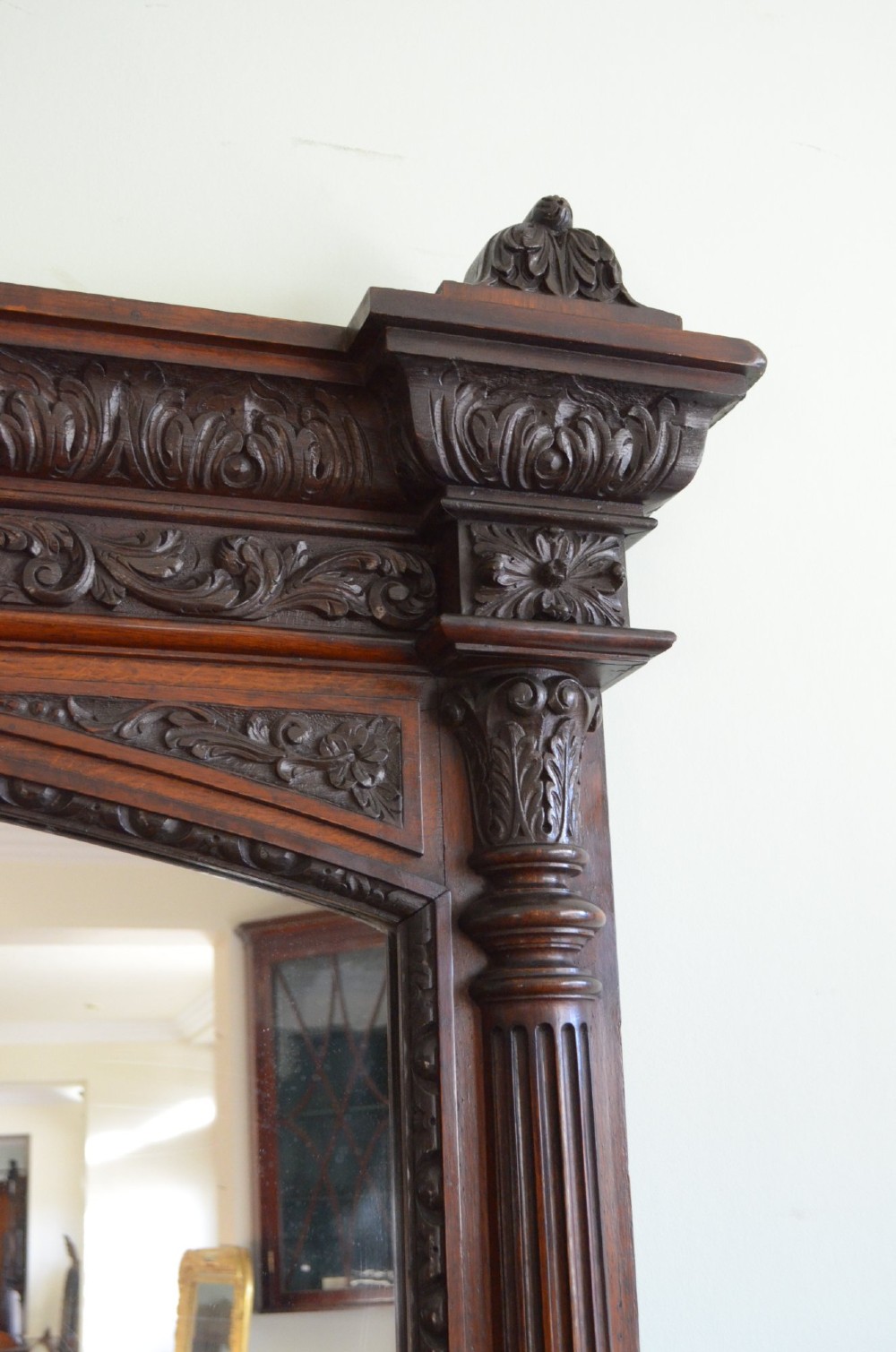 A tall 19th-century English solid oak mirror featuring an arched top, fluted column sides, and detailed hand-carved woodwork. View XIV