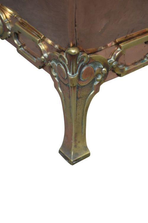 A late Victorian copper square vessel with rounded sides, ornate cast brass handles, decorative feet, and a fitted lid with a brass drop handle. View IV