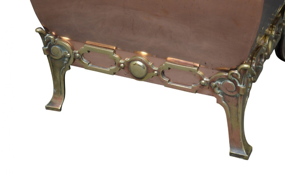 A late Victorian copper square vessel with rounded sides, ornate cast brass handles, decorative feet, and a fitted lid with a brass drop handle. View XI