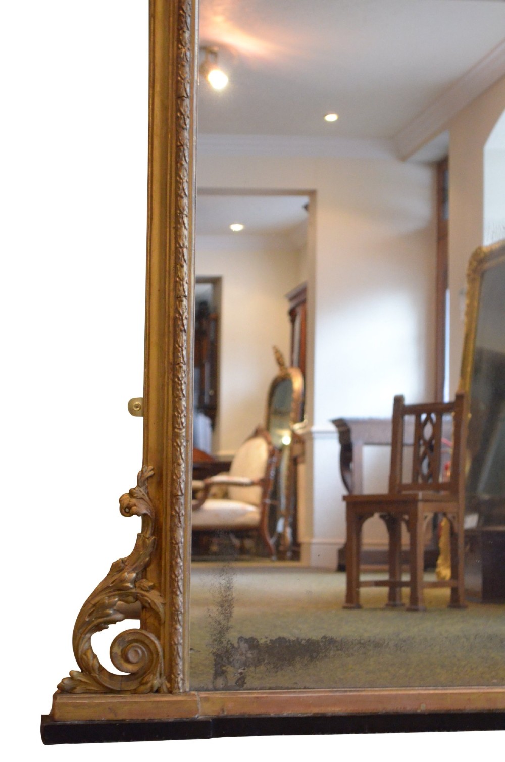 A large 19th-century English giltwood arched overmantel mirror featuring floral swag carvings at the crest and acanthus scroll feet at the base. View III