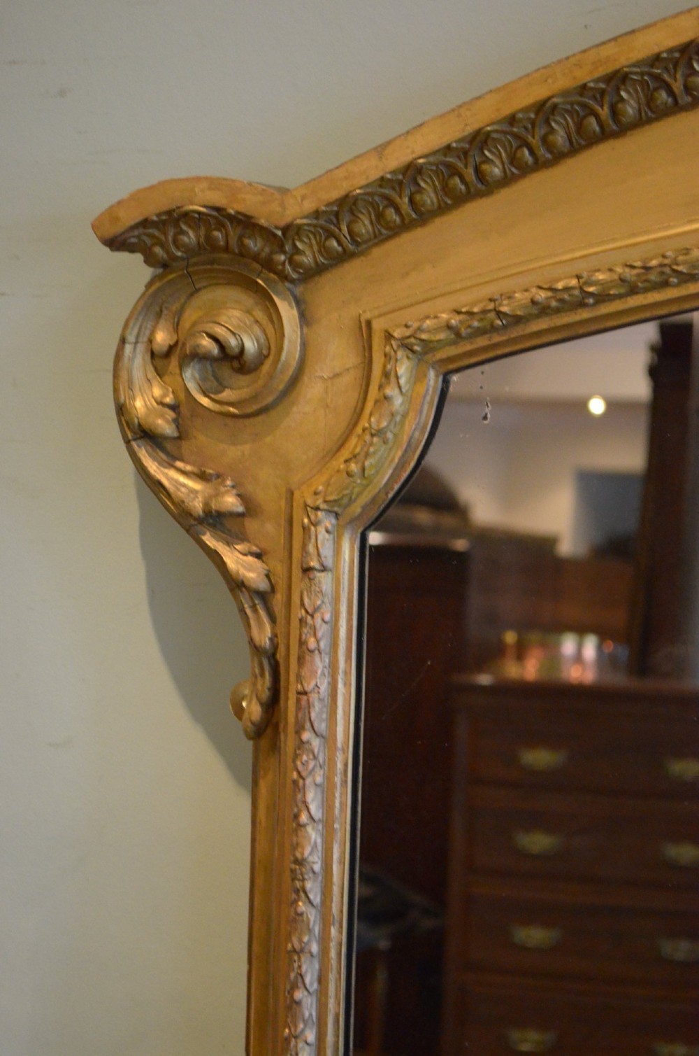 A large 19th-century English giltwood arched overmantel mirror featuring floral swag carvings at the crest and acanthus scroll feet at the base. View IV
