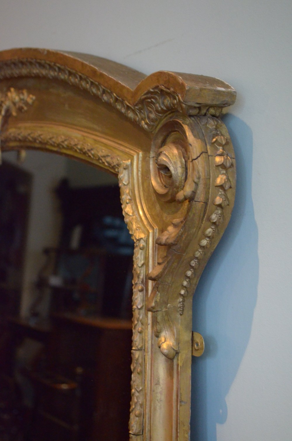 A large 19th-century English giltwood arched overmantel mirror featuring floral swag carvings at the crest and acanthus scroll feet at the base. View IX