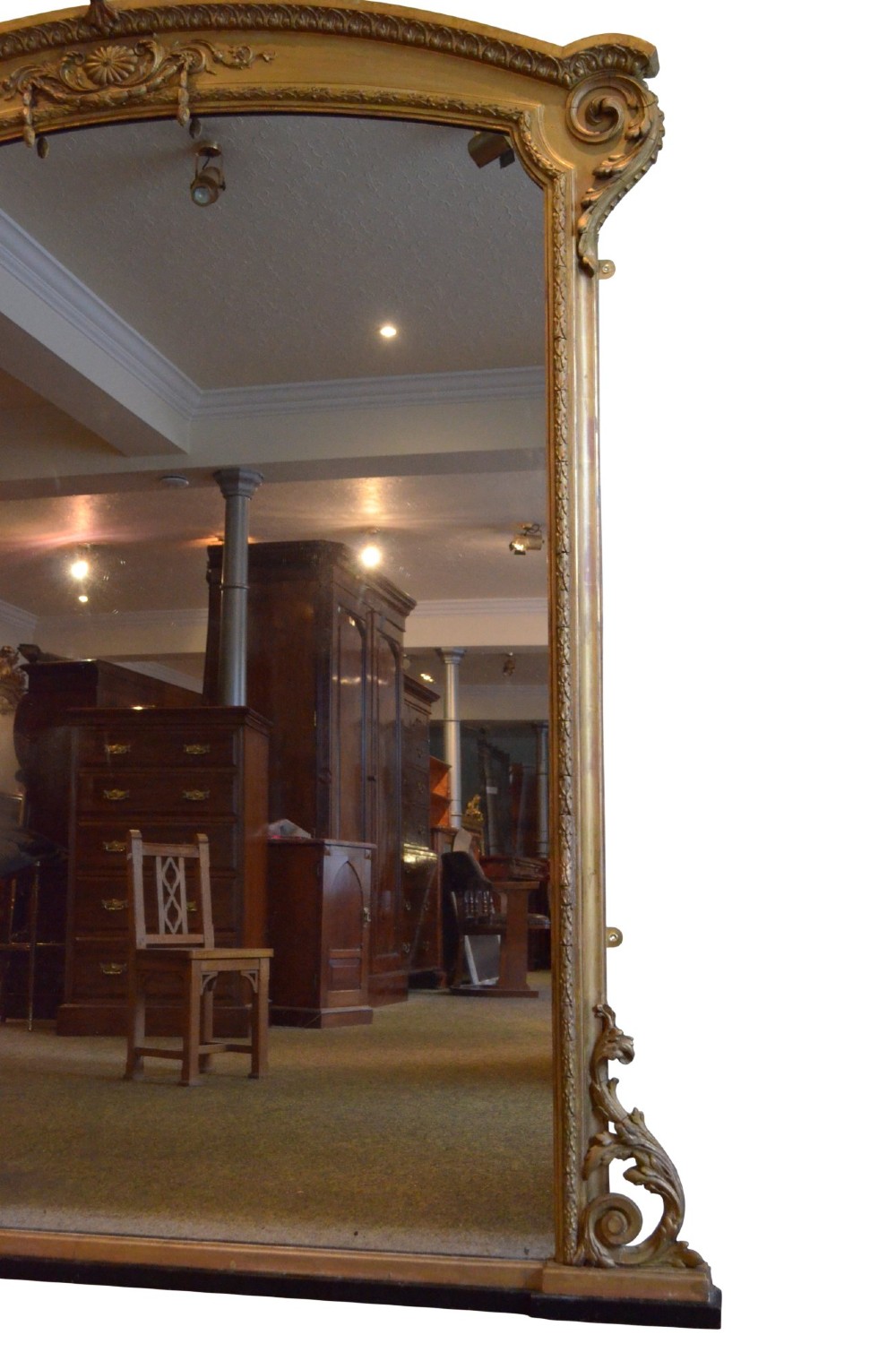 A large 19th-century English giltwood arched overmantel mirror featuring floral swag carvings at the crest and acanthus scroll feet at the base. View X