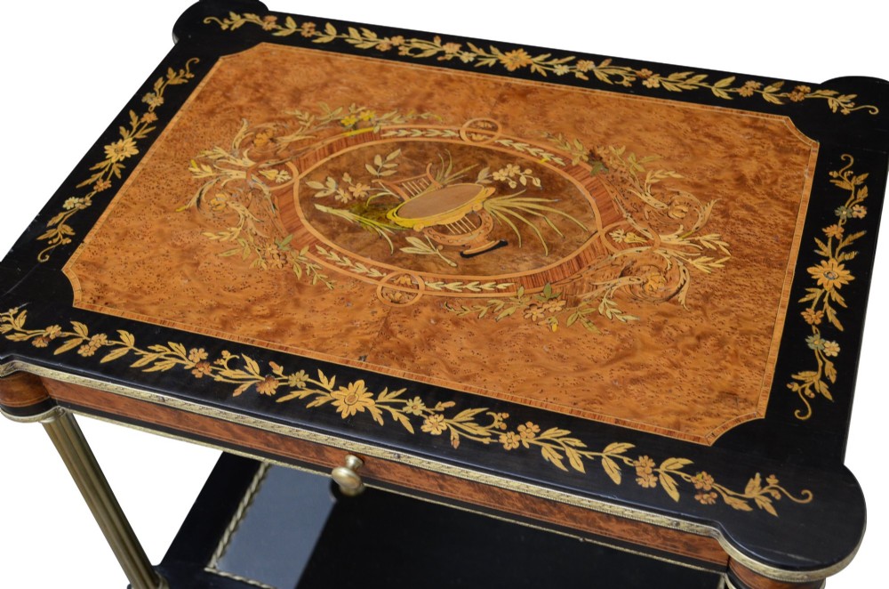 A late nineteenth-century French three-tier lamp table featuring a marquetry inlaid top with foliage border, slender brass columnar supports, two lower mirrored shelves, and brass hoof feet. View IV