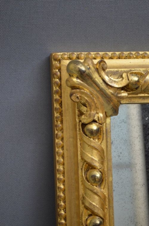 A rectangular Victorian giltwood overmantel mirror with carved rope twist moulding, corner scroll details, and original mirror glass. View VII