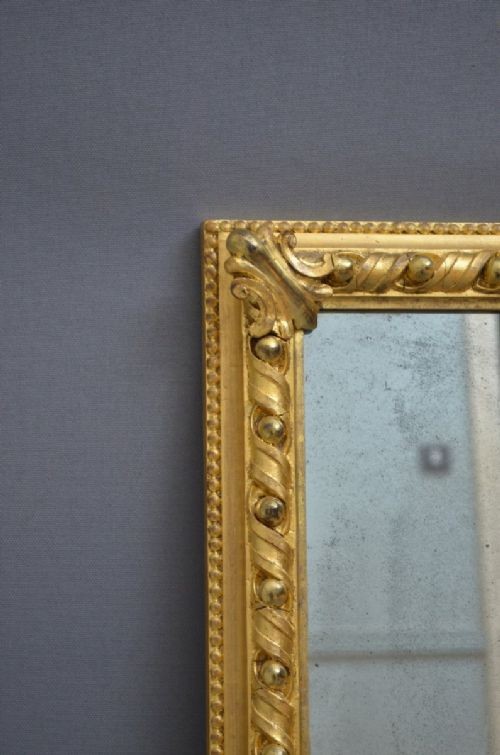 A rectangular Victorian giltwood overmantel mirror with carved rope twist moulding, corner scroll details, and original mirror glass. View XI
