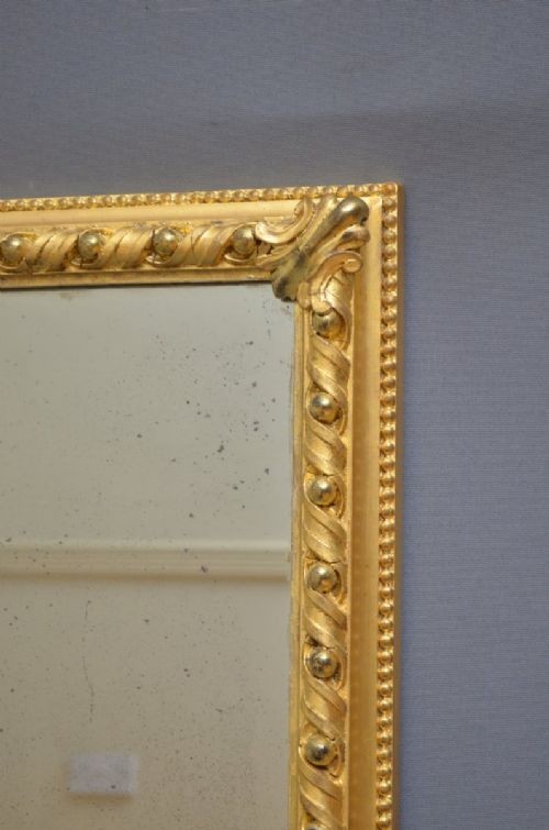 A rectangular Victorian giltwood overmantel mirror with carved rope twist moulding, corner scroll details, and original mirror glass. View XII