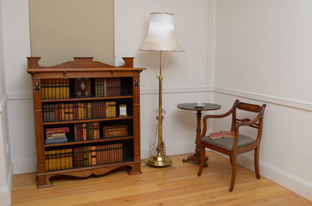 An Art Nouveau brass and copper standard lamp with a telescopic stem, scrolled metal base, and flared cream fabric shade. View II