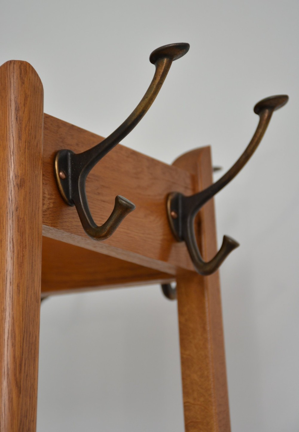 A tall, tapered oak coat stand featuring metal double hooks at the top, a square umbrella retaining rail in the centre, and a dark metal drip tray at the base. View II