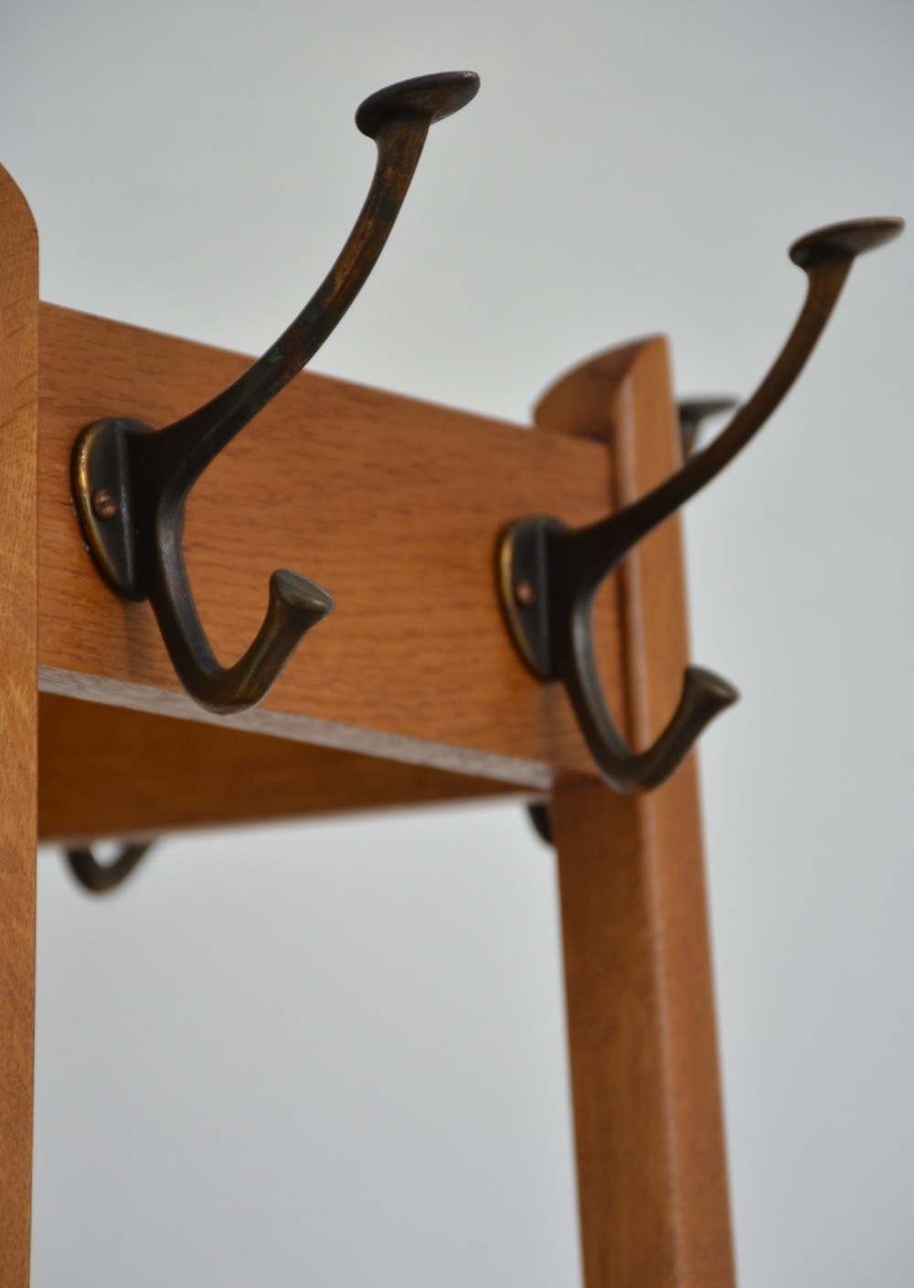 A tall, tapered oak coat stand featuring metal double hooks at the top, a square umbrella retaining rail in the centre, and a dark metal drip tray at the base. View IV