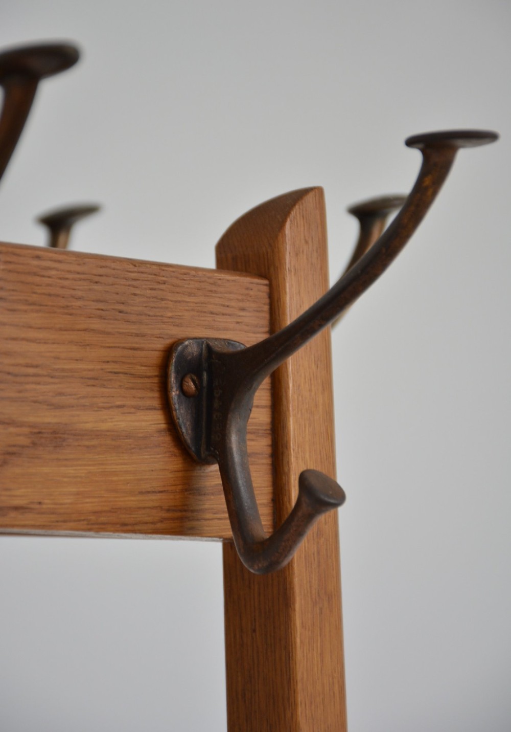 A tall, tapered oak coat stand featuring metal double hooks at the top, a square umbrella retaining rail in the centre, and a dark metal drip tray at the base. View XIII