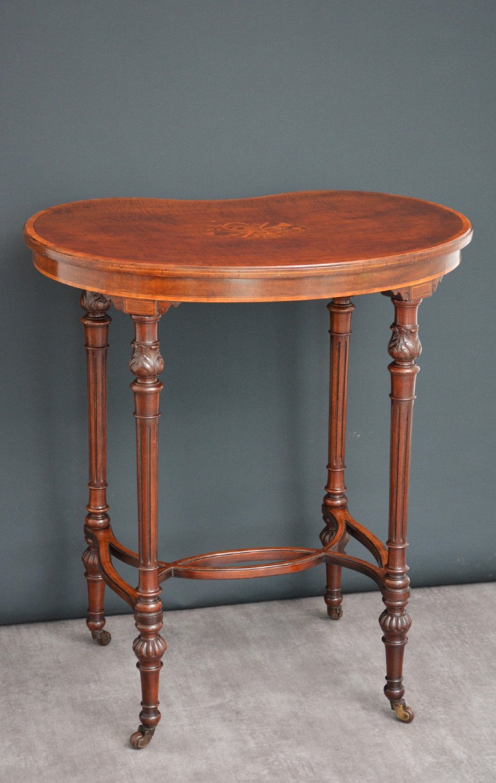 An Edwardian mahogany kidney-shaped side table featuring inlaid marquetry at the centre, fluted turned legs, a curved stretcher, and small brass castors. View III
