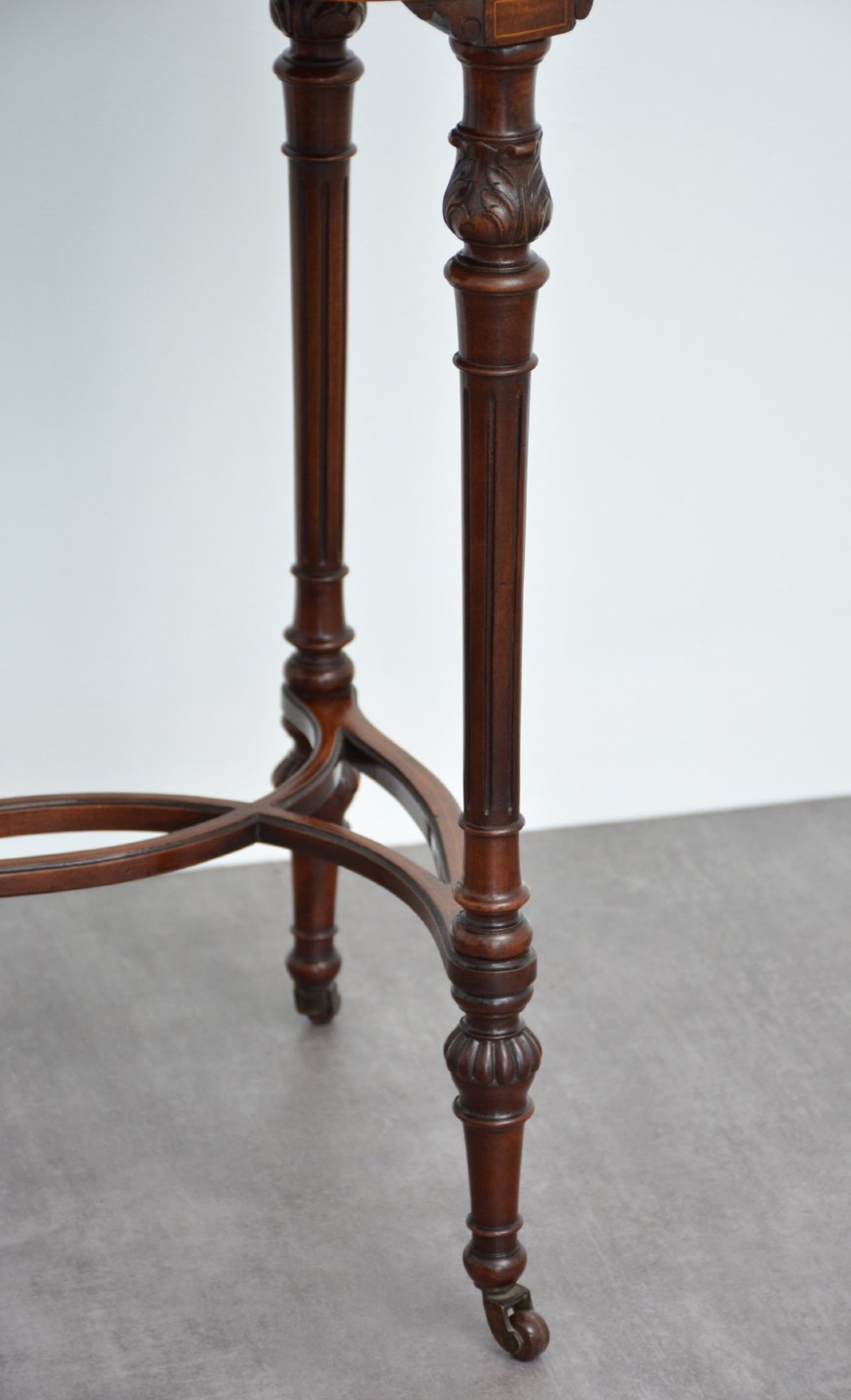 An Edwardian mahogany kidney-shaped side table featuring inlaid marquetry at the centre, fluted turned legs, a curved stretcher, and small brass castors. View IX