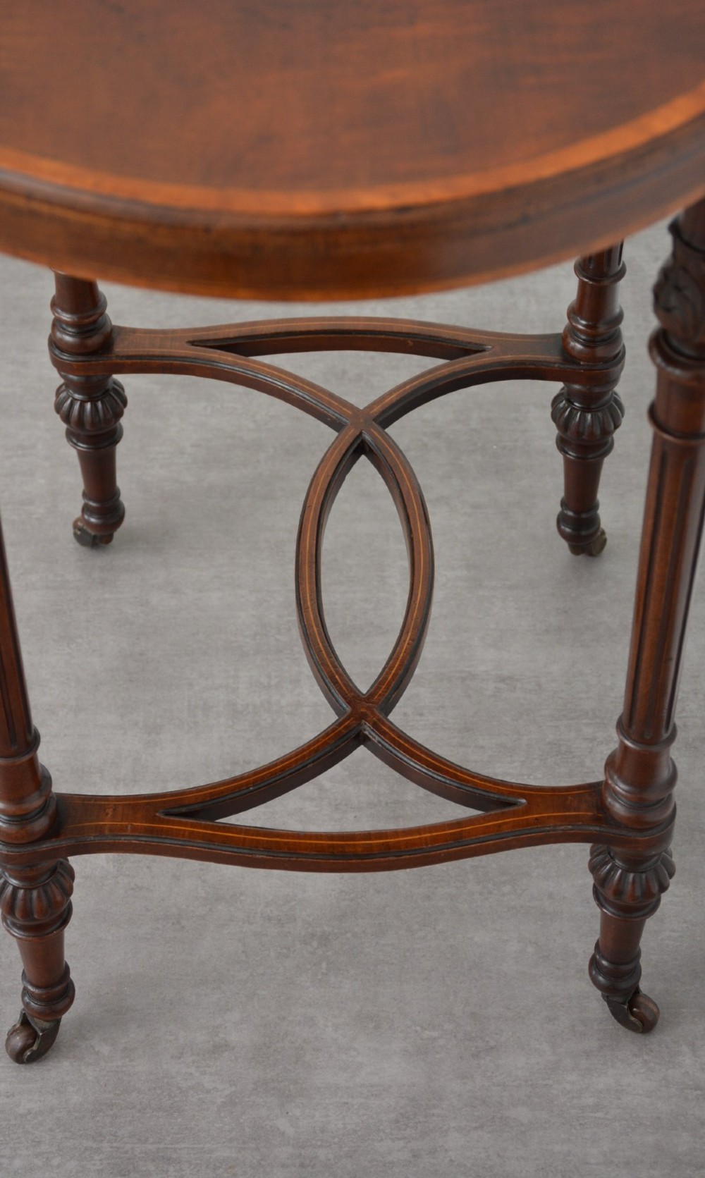 An Edwardian mahogany kidney-shaped side table featuring inlaid marquetry at the centre, fluted turned legs, a curved stretcher, and small brass castors. View XI
