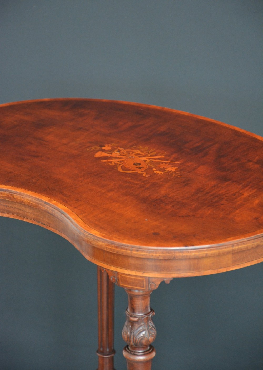 An Edwardian mahogany kidney-shaped side table featuring inlaid marquetry at the centre, fluted turned legs, a curved stretcher, and small brass castors. View XIII