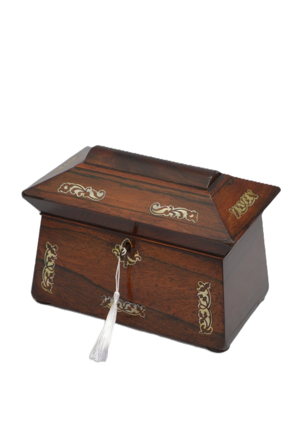 A Regency-era sarcophagus-shaped rosewood jewellery box featuring decorative scroll inlay and a key with a white tassel.