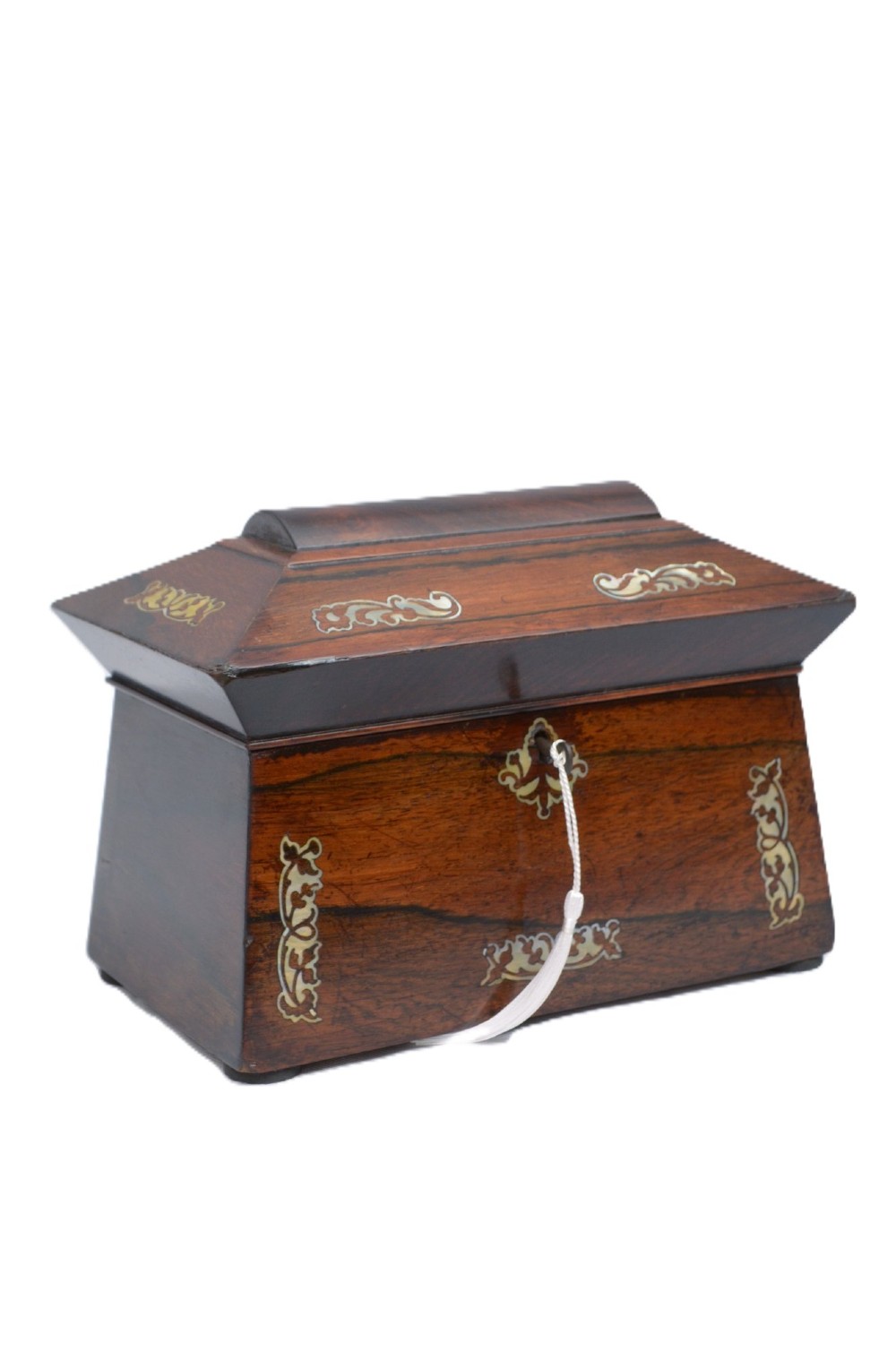 A Regency-era sarcophagus-shaped rosewood jewellery box featuring decorative scroll inlay and a key with a white tassel. View III