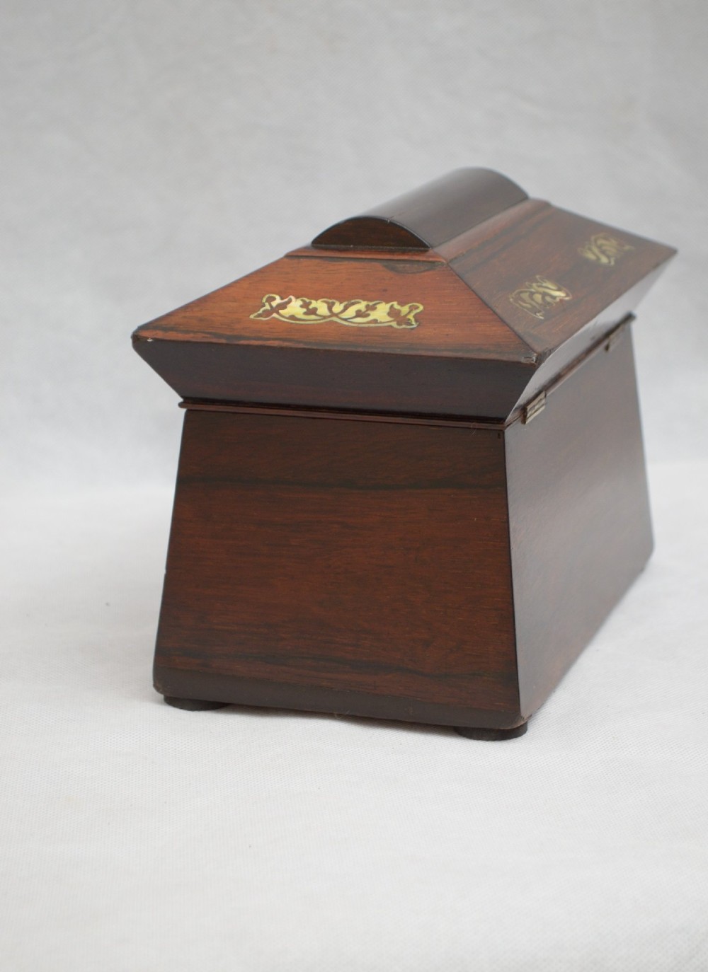 A Regency-era sarcophagus-shaped rosewood jewellery box featuring decorative scroll inlay and a key with a white tassel. View VII