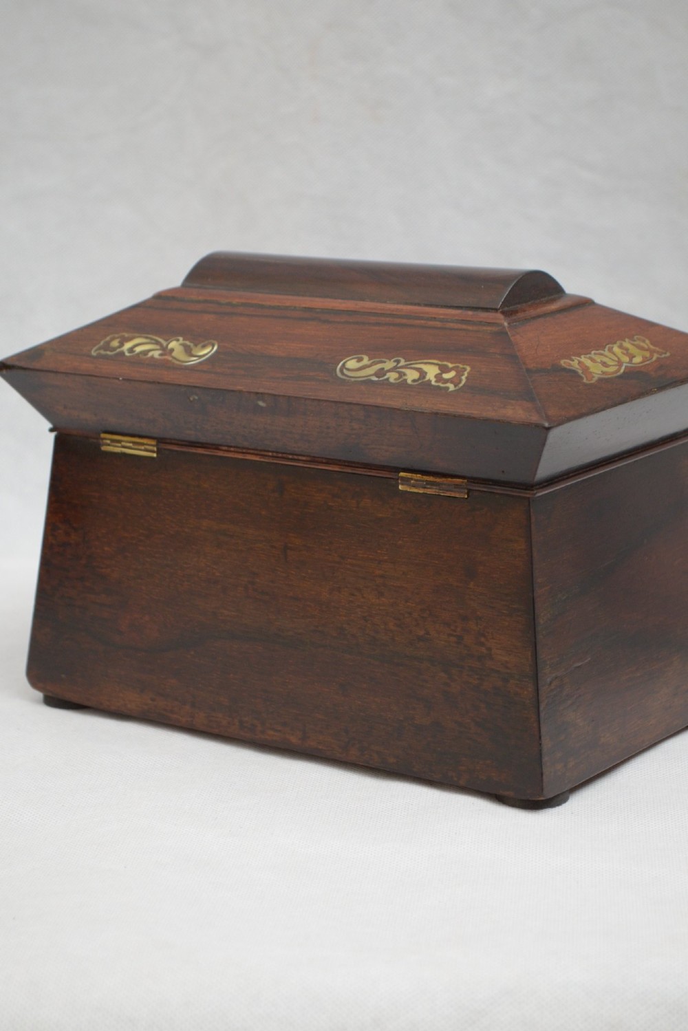 A Regency-era sarcophagus-shaped rosewood jewellery box featuring decorative scroll inlay and a key with a white tassel. View VIII