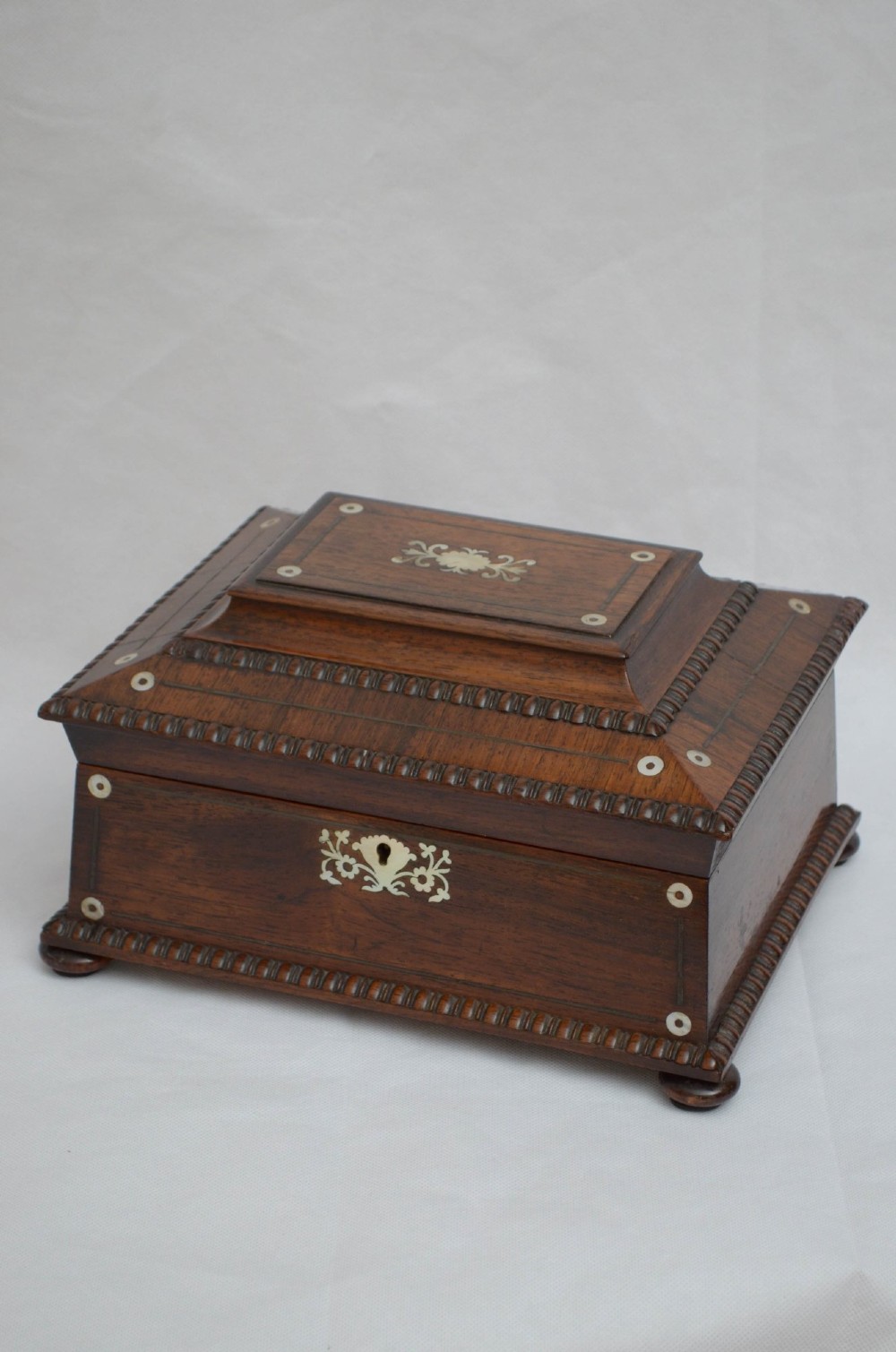 A William IV dark rosewood jewellery box featuring mother-of-pearl inlays, a tiered sarcophagus lid, carved gadrooned borders, and small bun feet. View VI