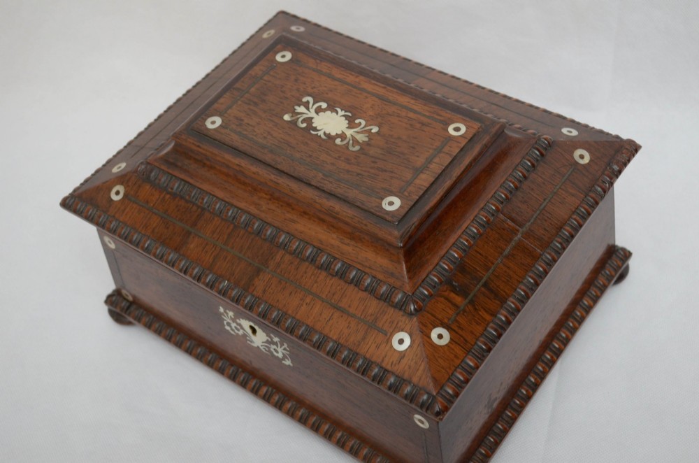A William IV dark rosewood jewellery box featuring mother-of-pearl inlays, a tiered sarcophagus lid, carved gadrooned borders, and small bun feet. View VII