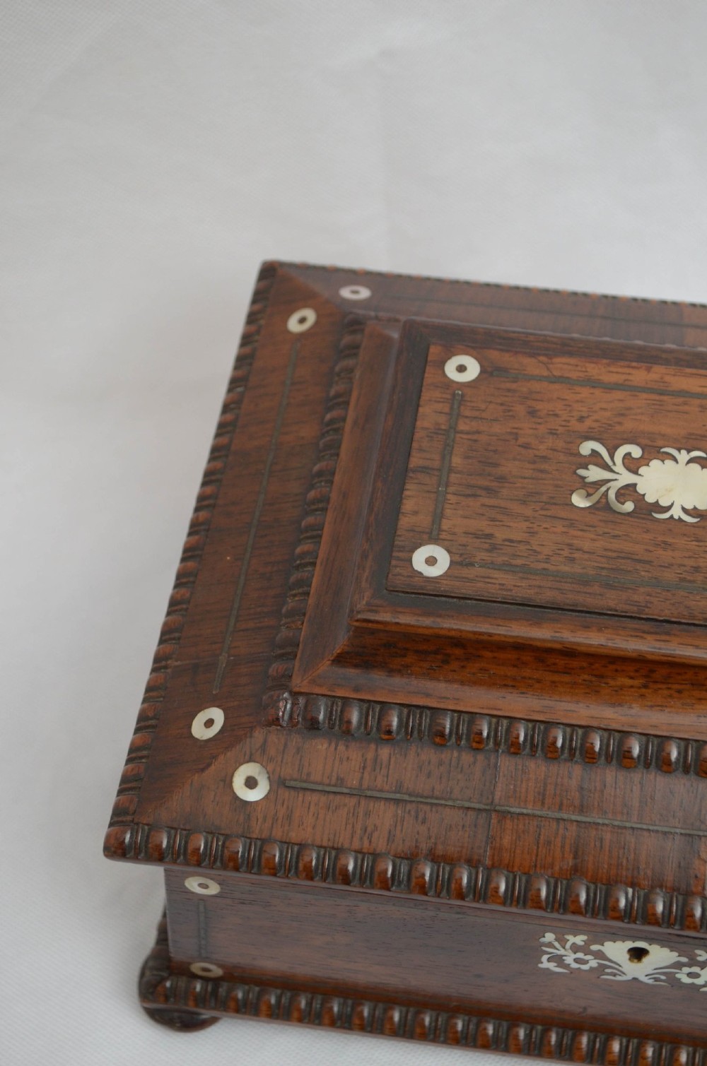 A William IV dark rosewood jewellery box featuring mother-of-pearl inlays, a tiered sarcophagus lid, carved gadrooned borders, and small bun feet. View VIII