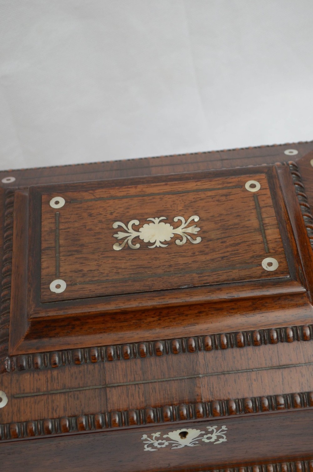 A William IV dark rosewood jewellery box featuring mother-of-pearl inlays, a tiered sarcophagus lid, carved gadrooned borders, and small bun feet. View IX