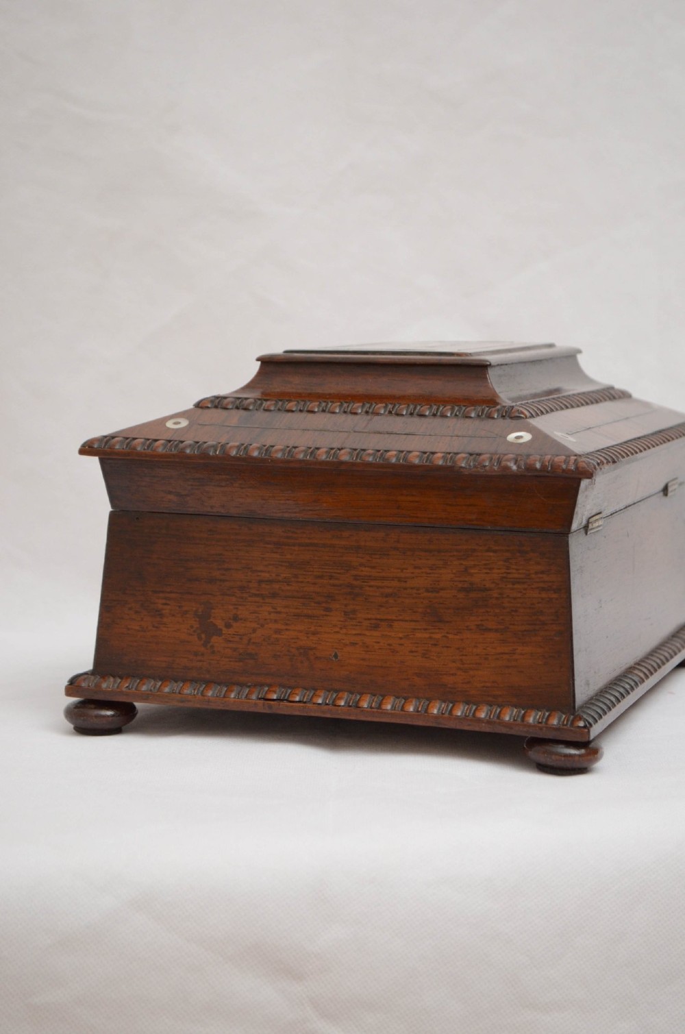 A William IV dark rosewood jewellery box featuring mother-of-pearl inlays, a tiered sarcophagus lid, carved gadrooned borders, and small bun feet. View XIV