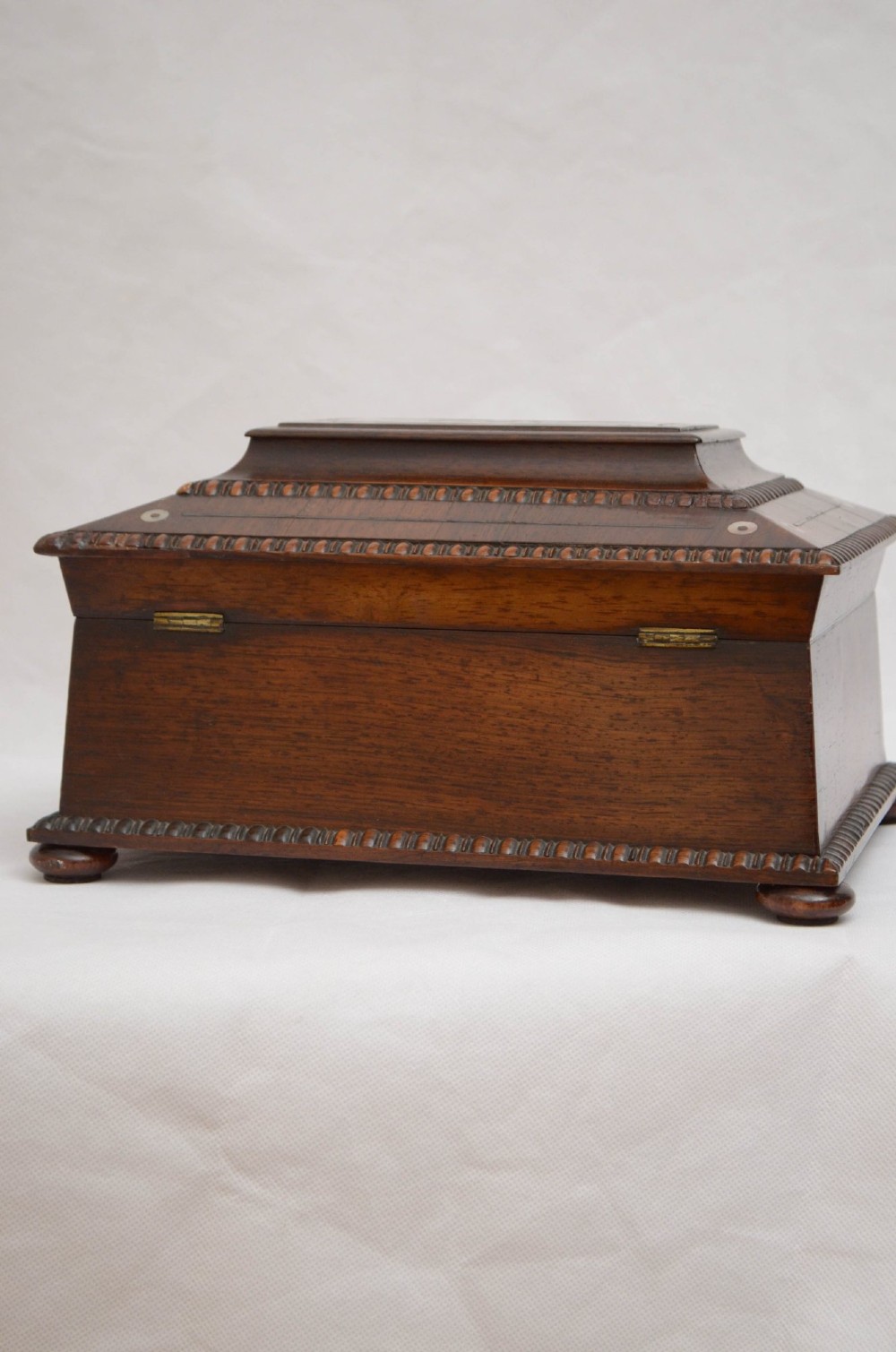 A William IV dark rosewood jewellery box featuring mother-of-pearl inlays, a tiered sarcophagus lid, carved gadrooned borders, and small bun feet. View XV