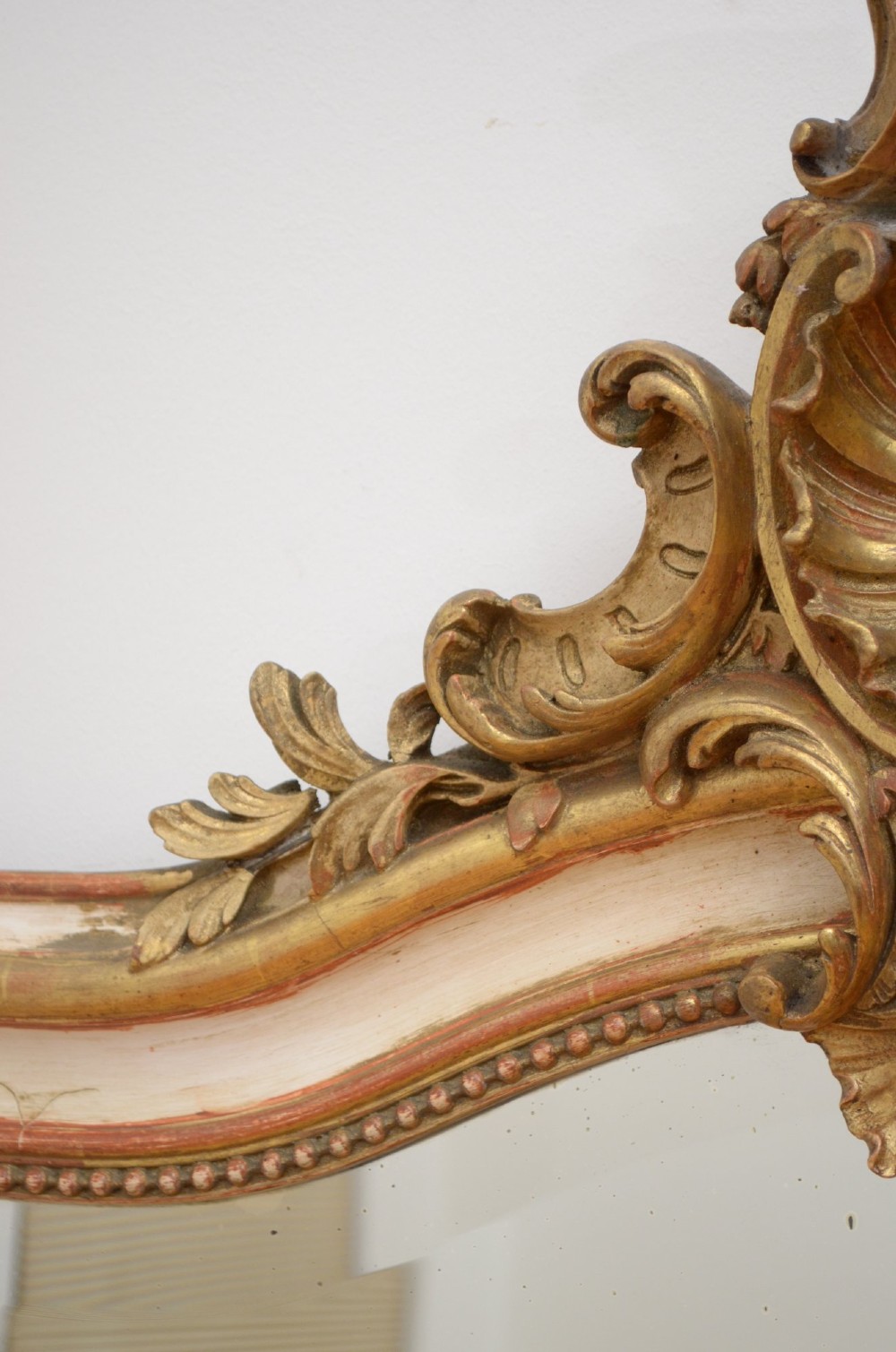 A tall 19th-century French wall mirror with a gilded gesso frame, arched top, ornate shell cresting, and mild foxing across the mirror plate. View V