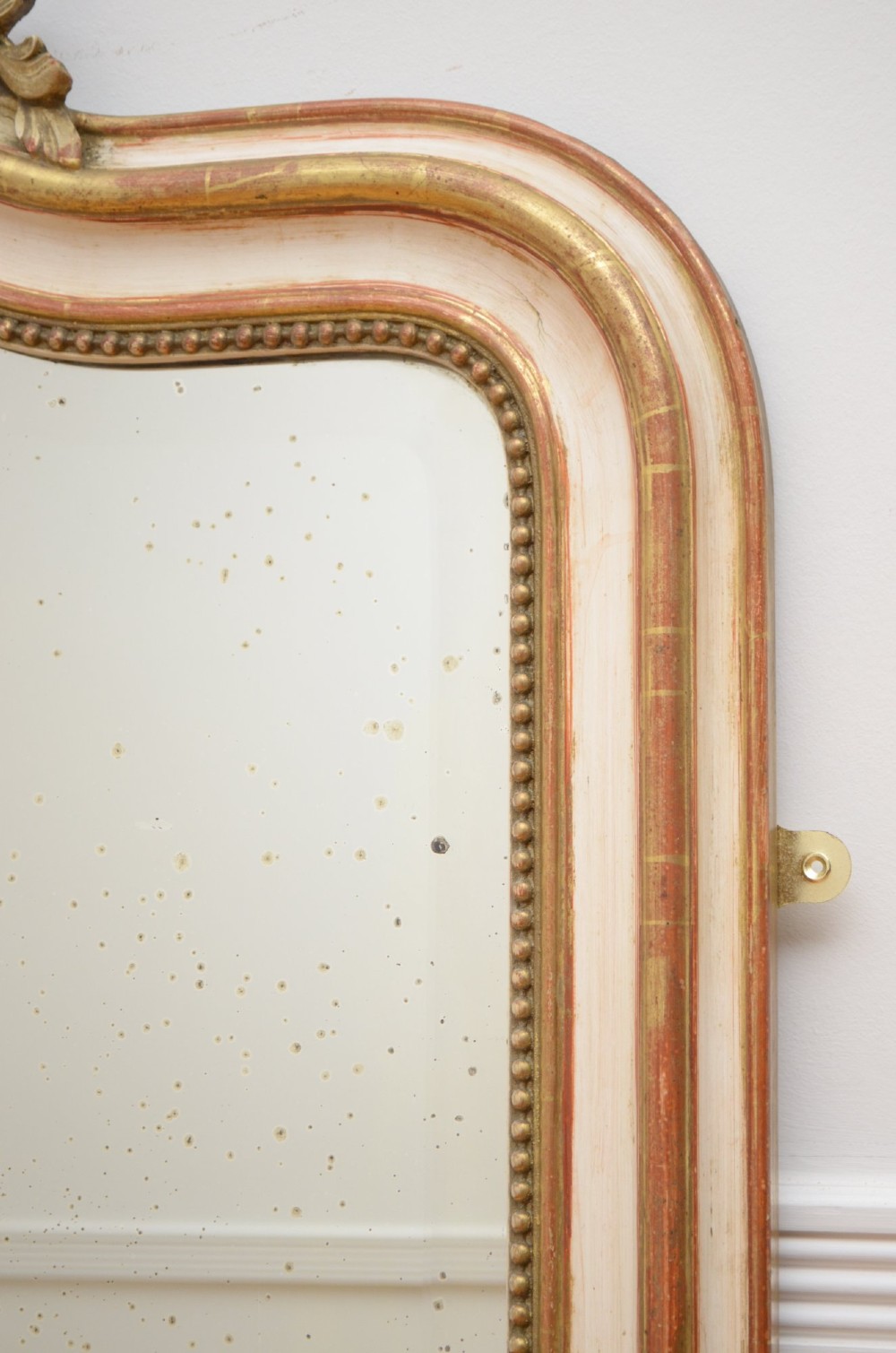 A tall 19th-century French wall mirror with a gilded gesso frame, arched top, ornate shell cresting, and mild foxing across the mirror plate. View X