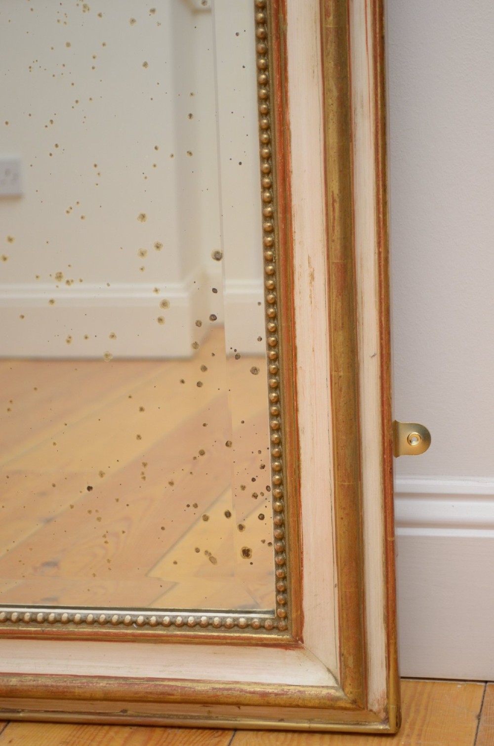 A tall 19th-century French wall mirror with a gilded gesso frame, arched top, ornate shell cresting, and mild foxing across the mirror plate. View XII
