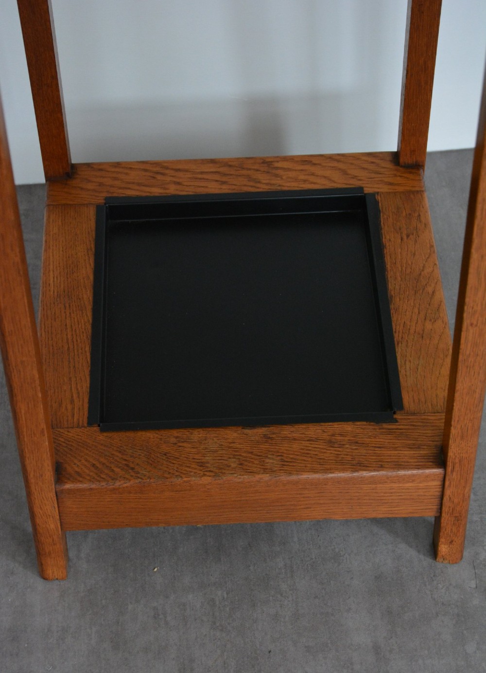 A tall tapered oak coat and umbrella stand featuring top metal hooks, an intermediate square divider, and a dark metal drip tray at the base. View XIV