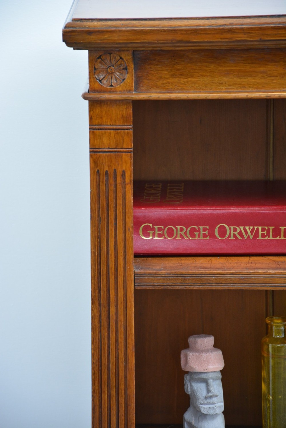 A late Victorian low solid oak open bookcase featuring three horizontal shelves, fluted pilasters, and carved corner rosettes. View III