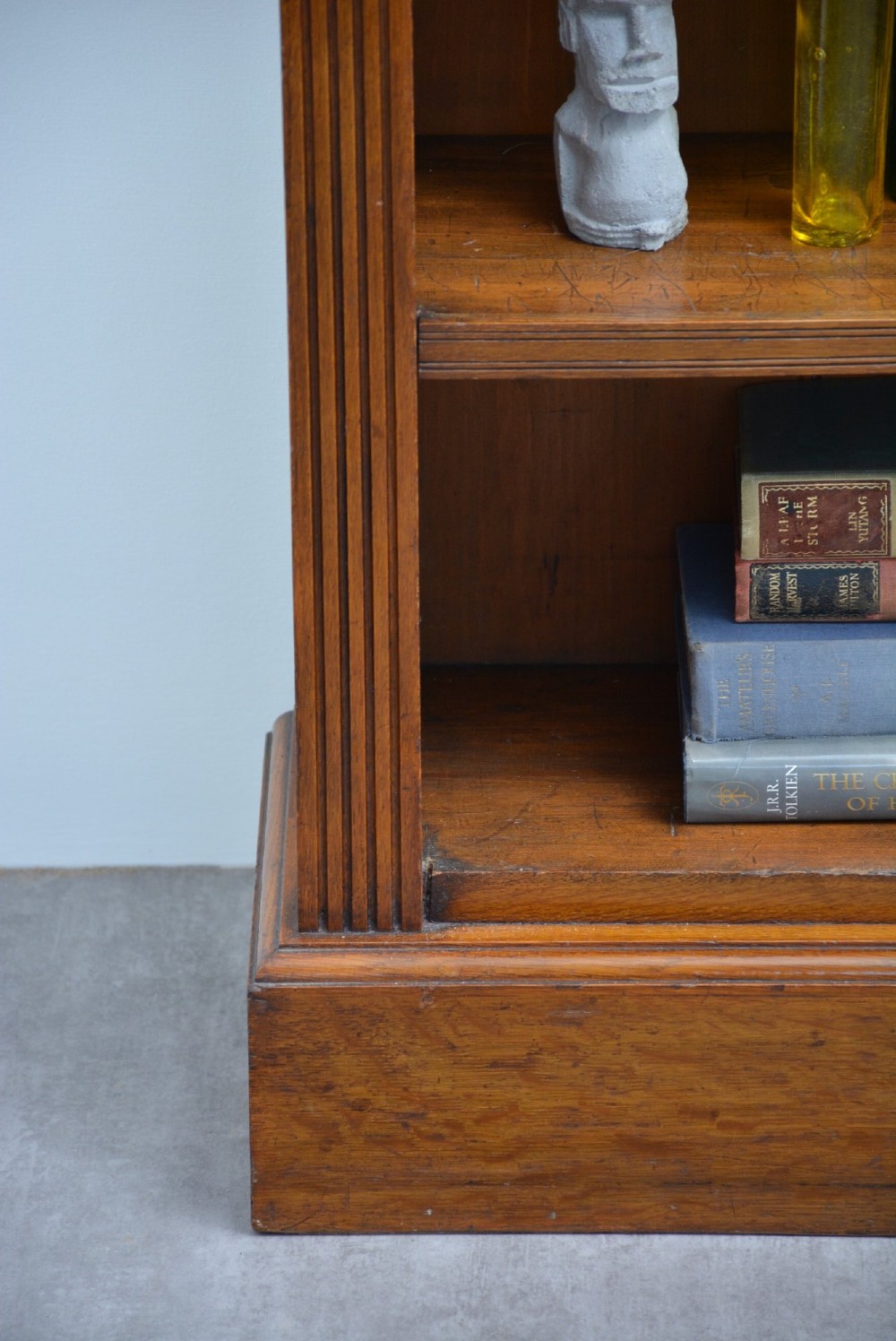 A late Victorian low solid oak open bookcase featuring three horizontal shelves, fluted pilasters, and carved corner rosettes. View IV
