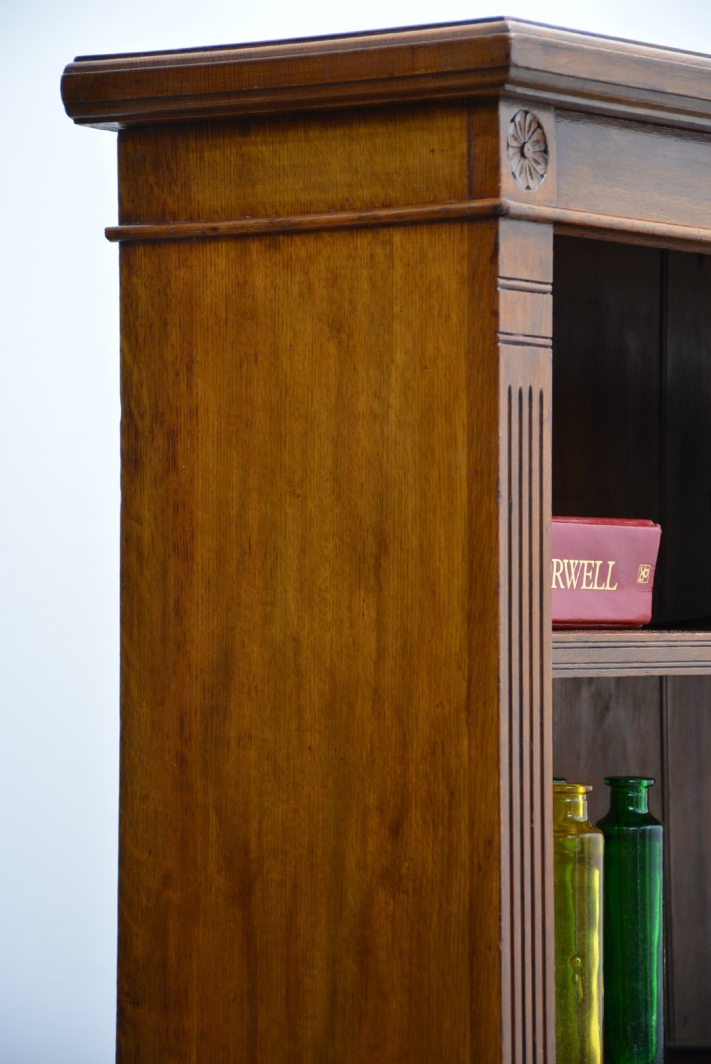 A late Victorian low solid oak open bookcase featuring three horizontal shelves, fluted pilasters, and carved corner rosettes. View VIII