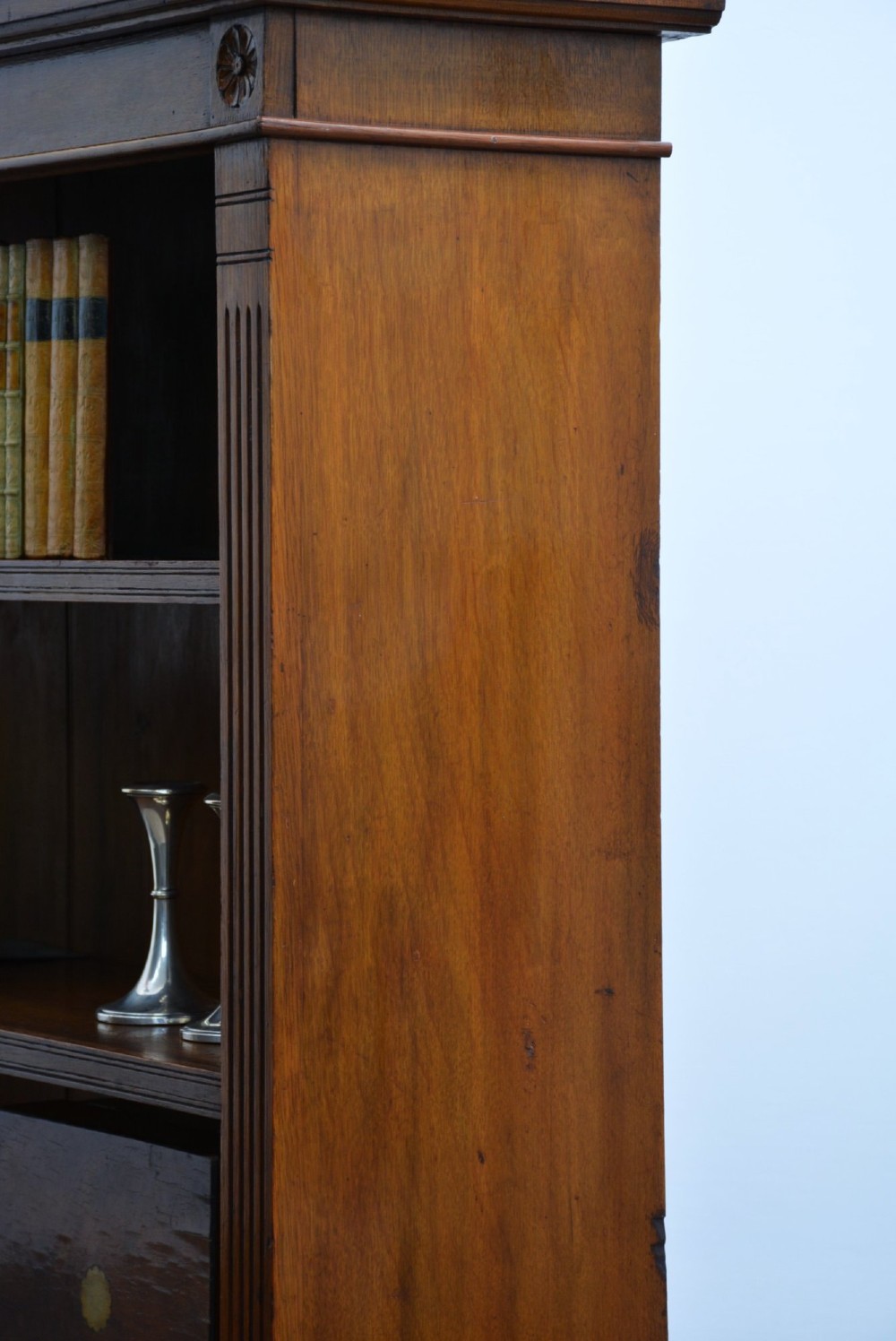 A late Victorian low solid oak open bookcase featuring three horizontal shelves, fluted pilasters, and carved corner rosettes. View X