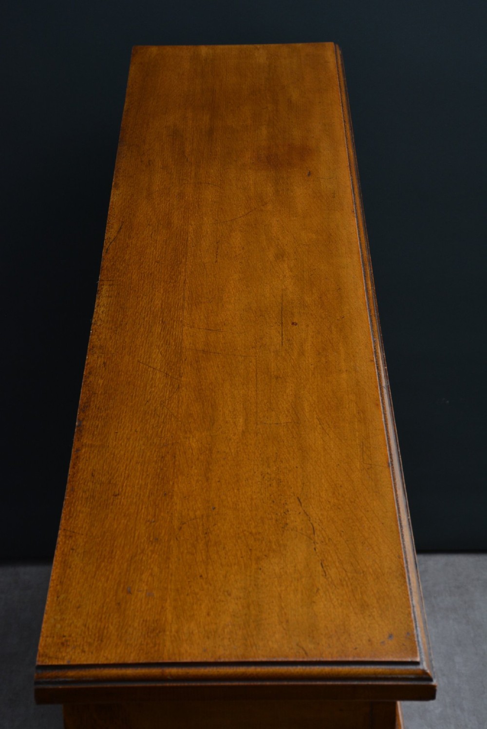 A late Victorian low solid oak open bookcase featuring three horizontal shelves, fluted pilasters, and carved corner rosettes. View XV