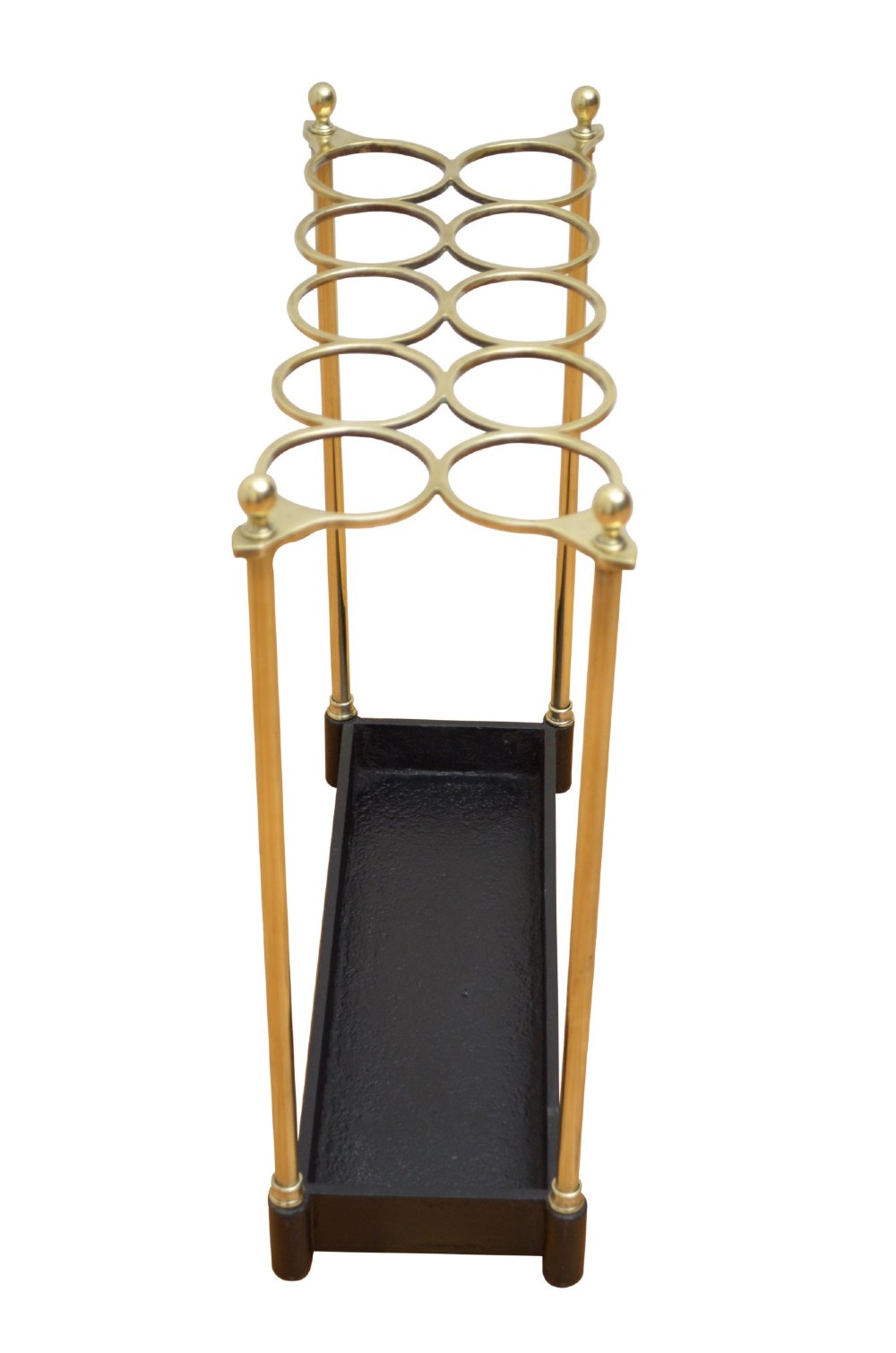 A late nineteenth-century brass umbrella stand featuring eight circular divisions, four upright columns topped with ball finials, and a black cast iron drip tray base. View VIII