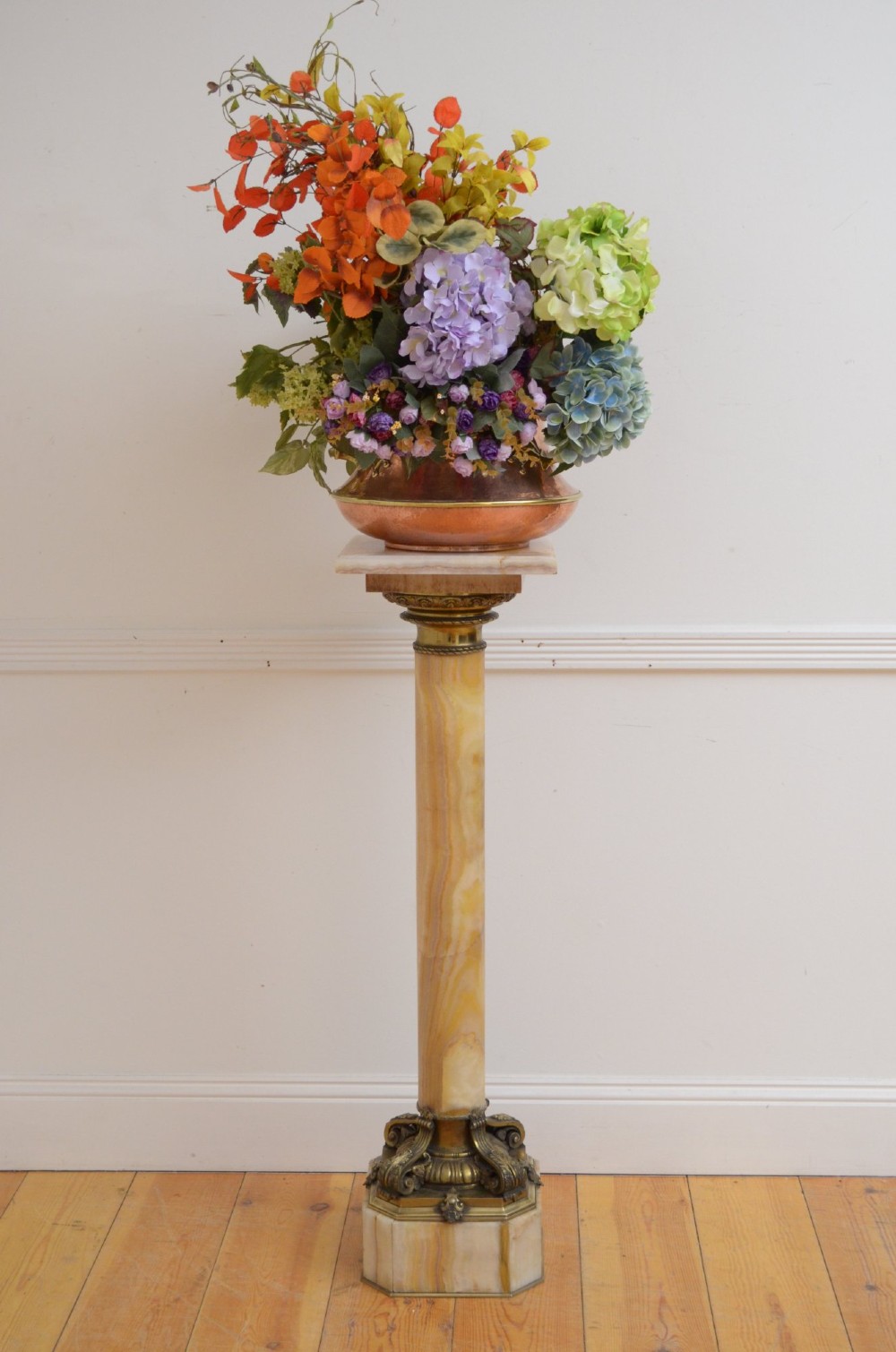 A tall cylindrical cream and amber onyx column featuring gilt bronze ormolu mounts at the top and base, set on a square plinth. View XI