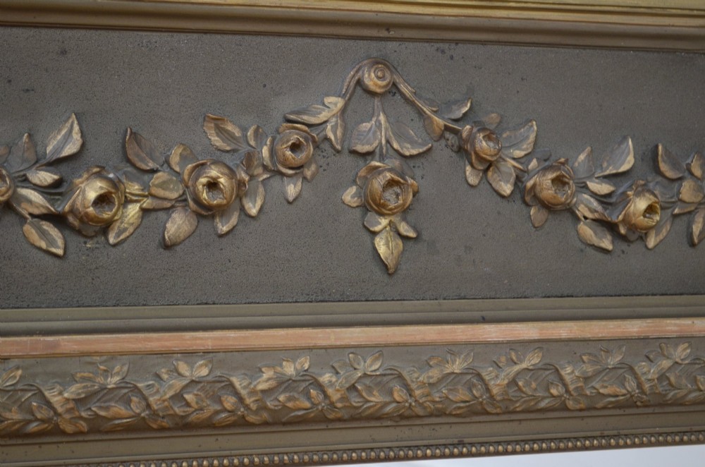 A large rectangular French wall mirror featuring a gilded wood frame, an olive green painted frieze decorated with carved floral swags, and an ornate ribbon bow crest. View IX