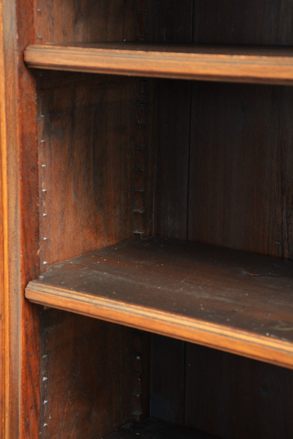 A late Victorian open walnut bookcase featuring a carved rosette frieze, moulded top cornice, adjustable shelves, and a solid plinth base. View III