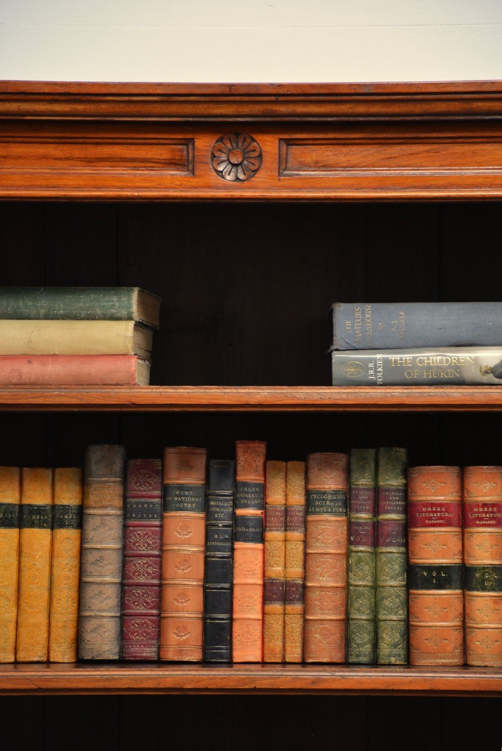 A late Victorian open walnut bookcase featuring a carved rosette frieze, moulded top cornice, adjustable shelves, and a solid plinth base. View X